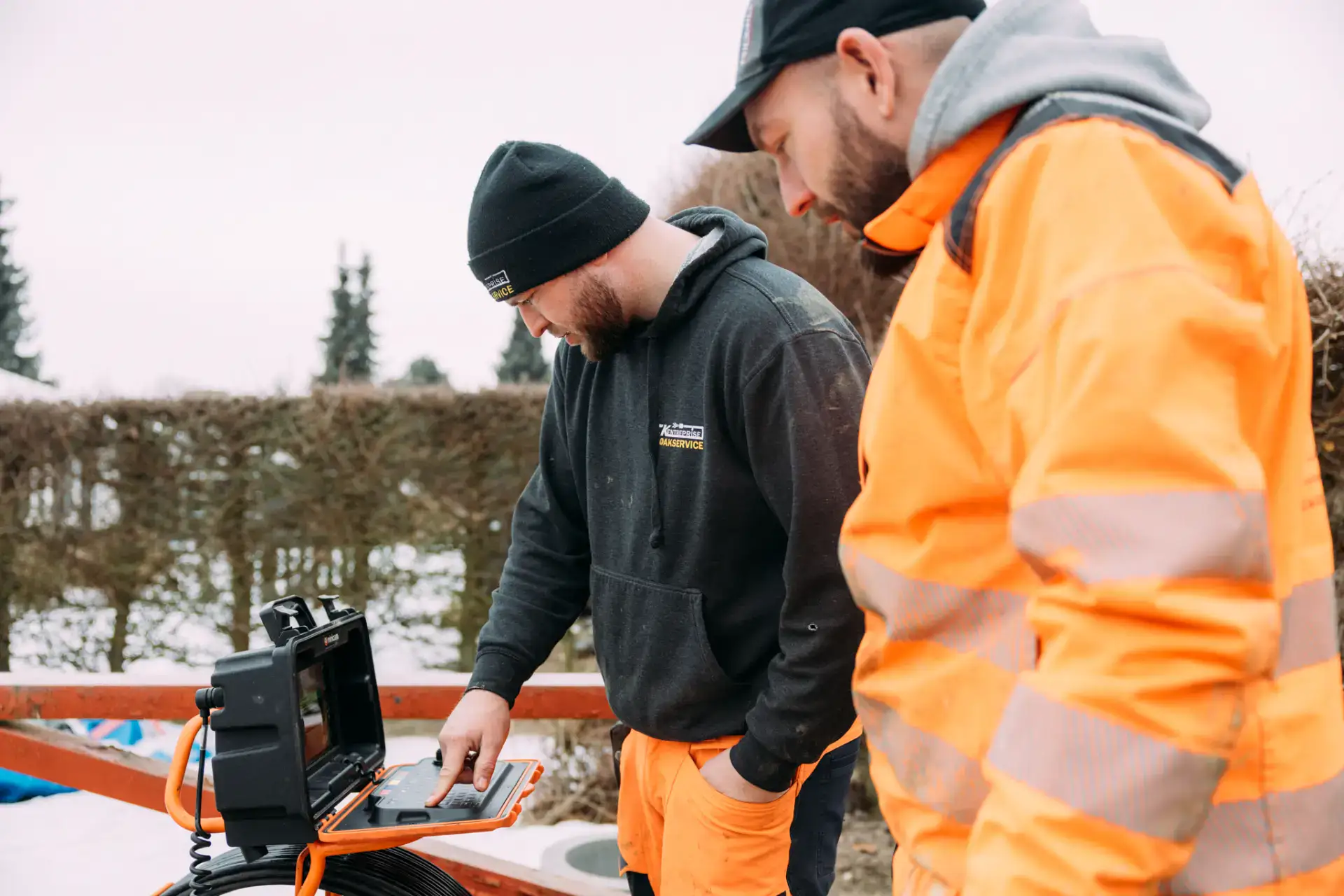 Kloakservice i aktion med to teknikere, der arbejder på udendørs kloaksystem.