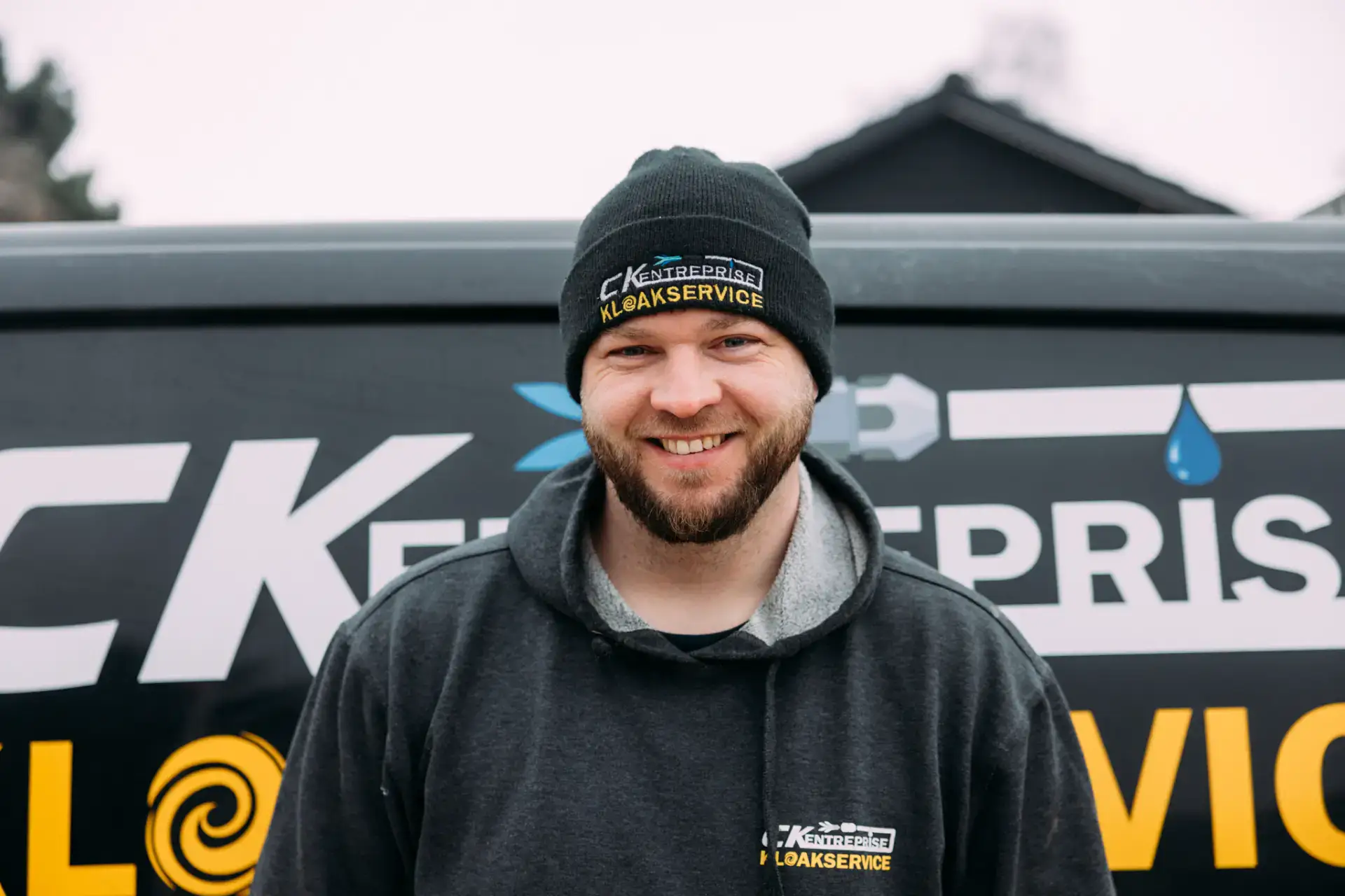 Mand i CK Kloakservice uniform foran firmabil, klar til kloakarbejde.