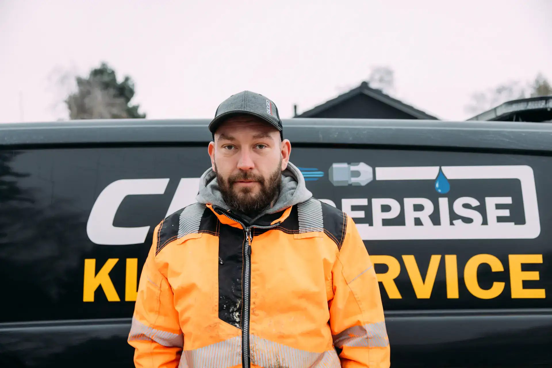 Kloakservice ekspert med uniform foran firmabil.