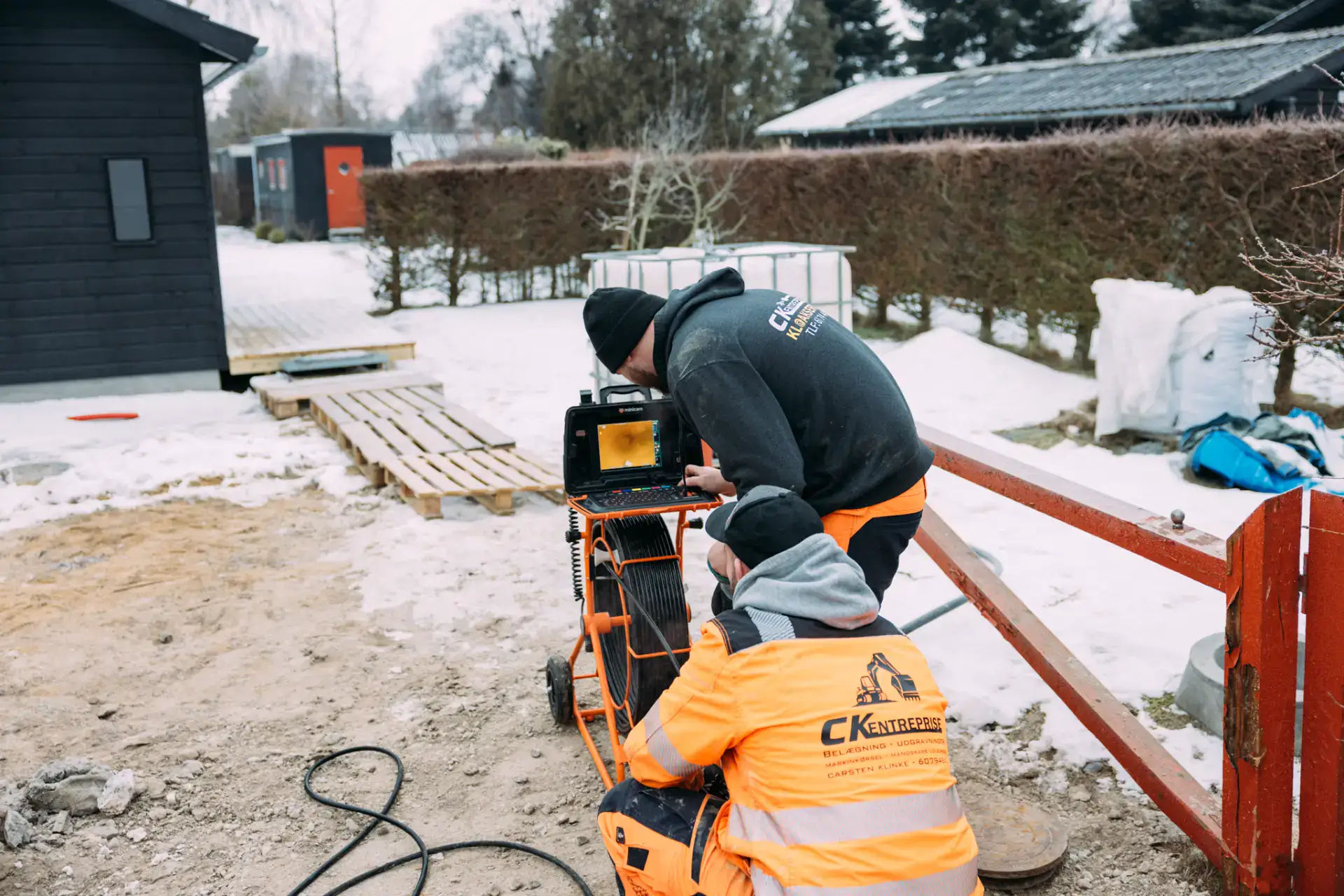 Kloakservice ekspert, der arbejder på afløb i vintervejr.