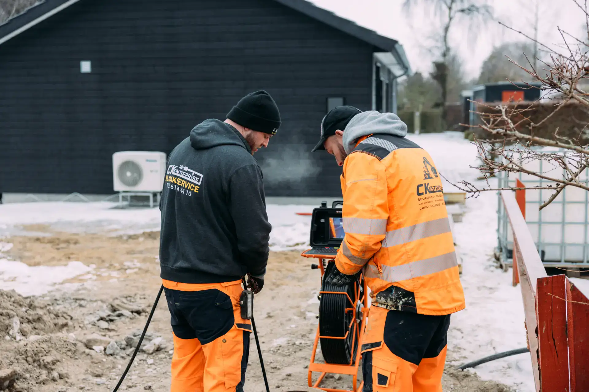 To kloakarbejdere arbejder med udstyr på byggepladsen i vintervejr.